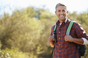 Naklejka na ściany i meble Portrait Of Man Hiking In Countryside Wearing Backpack