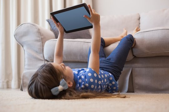 Little girl using digital tablet in the living room