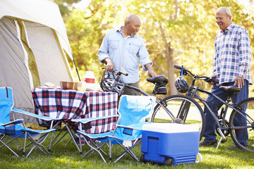 Two Senior Men Riding Bikes On Camping Holiday
