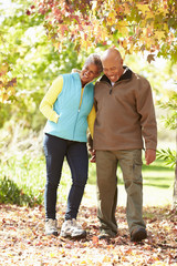 Senior Couple Walking Through Autumn Woodland