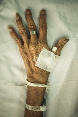 hand of old patient with plug on bed in hospital