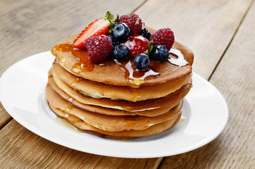 Pancakes with berries and honey closeup