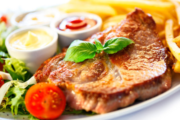 Grilled steaks, French fries and vegetables (shallow DOF)