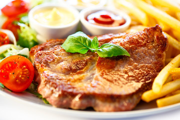 Grilled steaks, French fries and vegetables (shallow DOF)