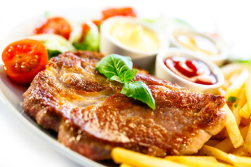 Grilled steaks, French fries and vegetables (shallow DOF)