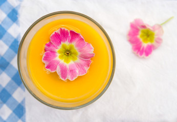 Fototapeta na wymiar yellow juice,glass, pink flowers,blue napkin,top view