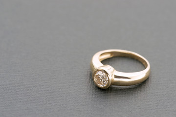Gold ring with 1 carat diamond on grey background