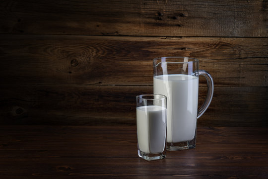 glass and carafe of milk on wooden background