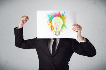 Businessman holding a cardboard with paint splashes and lightbul
