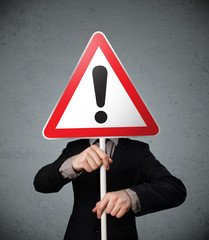 Businessman holding an exclamation road sign