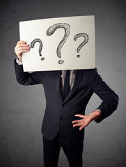 Businessman holding a paper with question marks in front of his