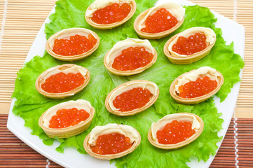 Tartlets with red caviar and butter on a plate