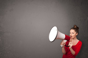 Girl shouting into megaphone on copy space background