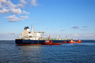 A huge oil tanker and three tugboats at work.