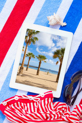 tablet on beach towels with sunbathing accessories