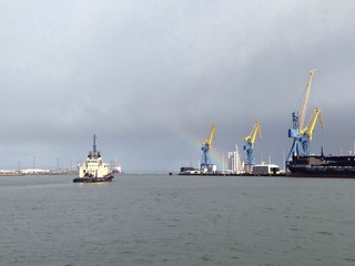 boat leaving harbor with rainbow on the horizon