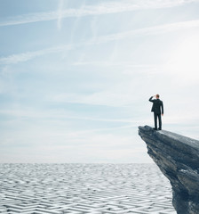 Businessman standing on a rock and looking at huge maze