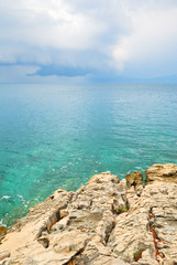 Blue sea and clouds with jagged cliffs in the foreground