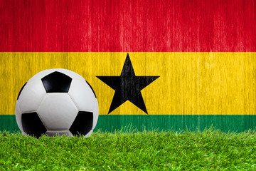 Soccer ball on grass with Ghana flag background