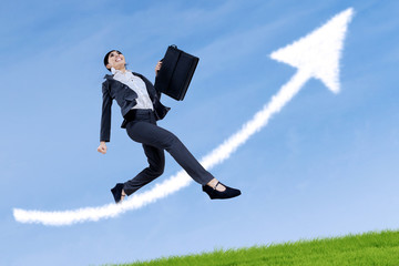 Business woman jumping with arrow sign