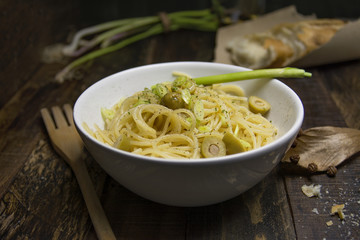 Close up shot of a white bowl filled with spaghetti pasta and ol