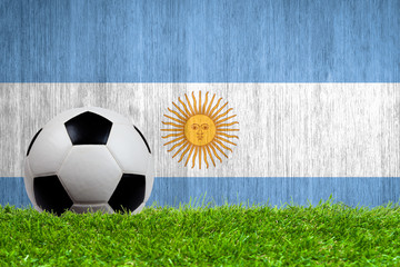 Soccer ball on grass with Argentina flag background