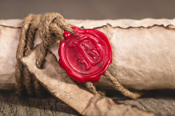 Old scroll paper on wooden background. Close up of wax seal.
