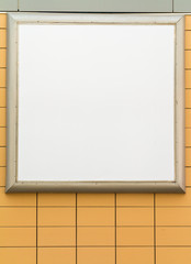 Blank square white advertising billboard on orange tiled wall