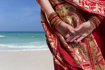 Close up of hands and bangles of a woman on the beach.