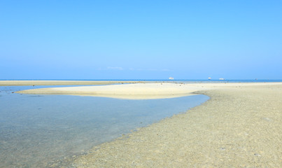 White beach sand with bright blue sea and sky