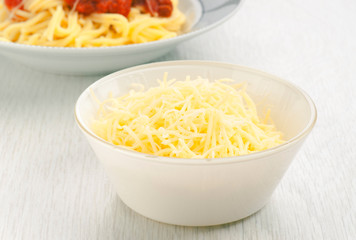 bowl of grated cheese to the bottom plate of spaghetti