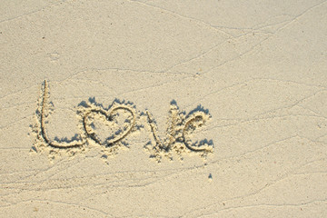 Love text wrote on white beach sand