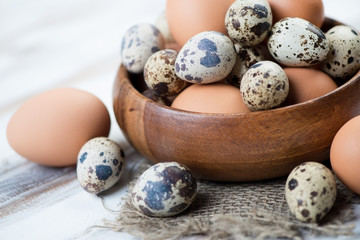Wooden bowl with raw chicken and quail eggs, close-up