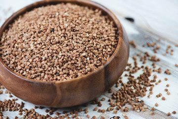 Close-up of a wooden bowl with raw buckwheat kernels
