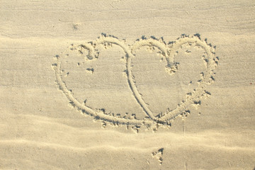 Couple hearts shape drawn on white beach sand