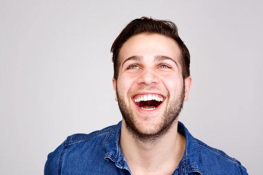 Young man laughing and looking up on isolated gray background