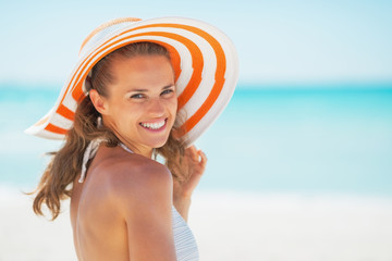 Portrait of smiling young woman in hat on beach