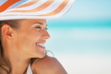 Portrait of smiling woman in hat on beach looking on copy space