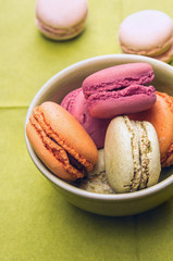 colorful macarons in bowl on green table