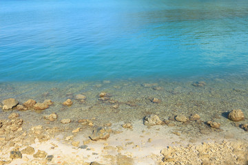 Clear green sea  white sand and coral reef on sunny day