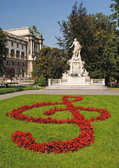 Statue of Amadeus Mozart with flower beds as treble clef in Burg