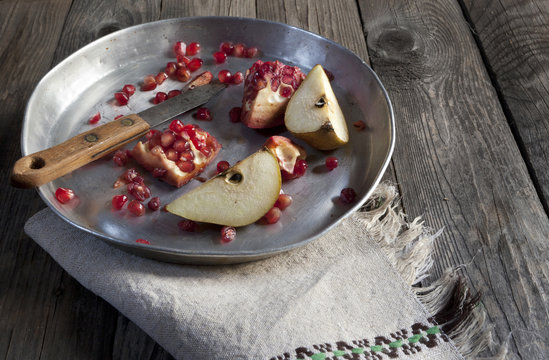 fruits composition pomegranate and pear on tray on wooden table