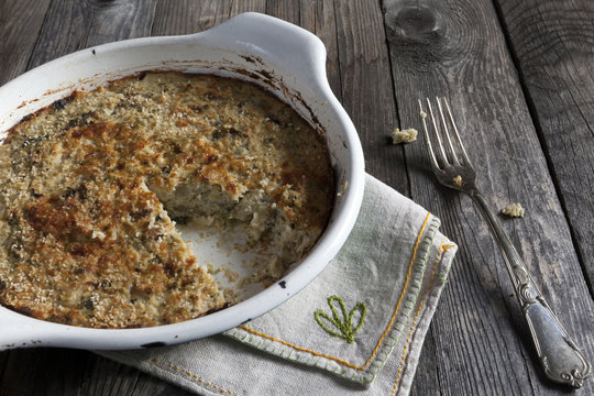 vegetables au gratin on casserole with fork on wooden table