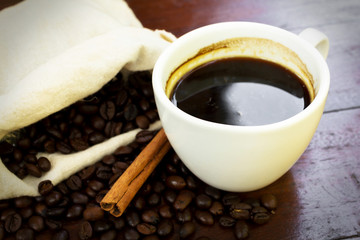 Coffee cup with beans and cinnamon stick.