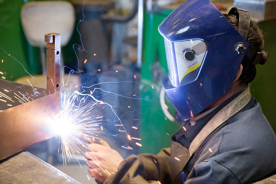 Welder working at factory with sparks and smoke