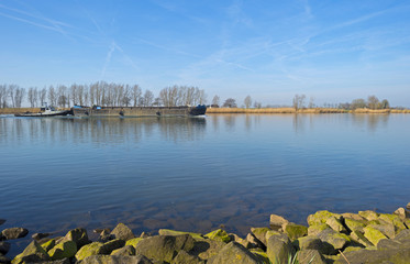 Barge sailing on a river under a clear sky