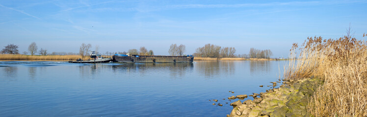 Barge sailing on a river under a clear sky