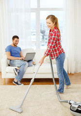 smiling woman with hoover and man with laptop