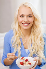 smiling woman with bowl of muesli having breakfast