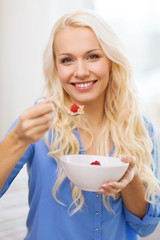 smiling woman with bowl of muesli having breakfast